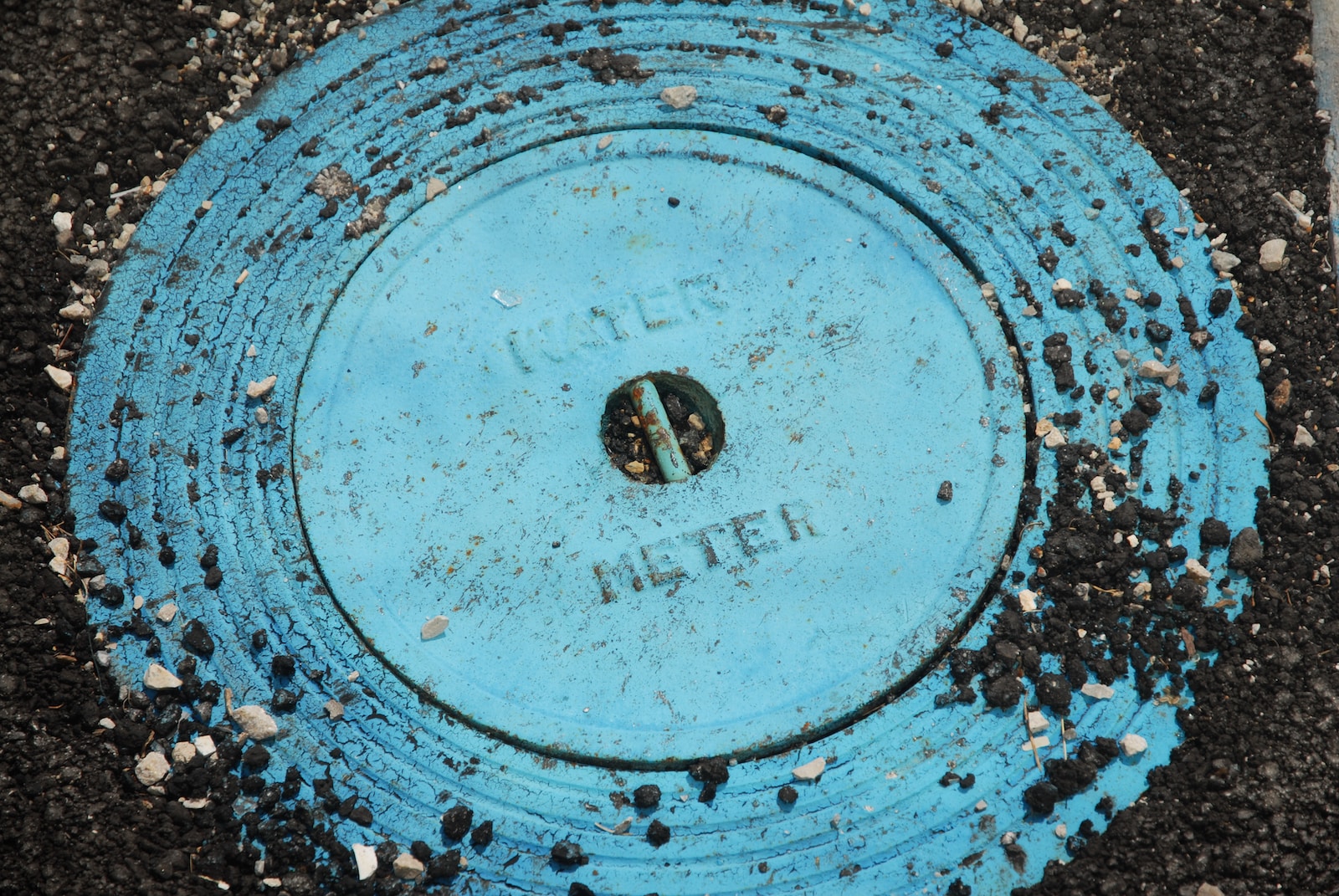 a blue fire hydrant sitting on top of a black ground